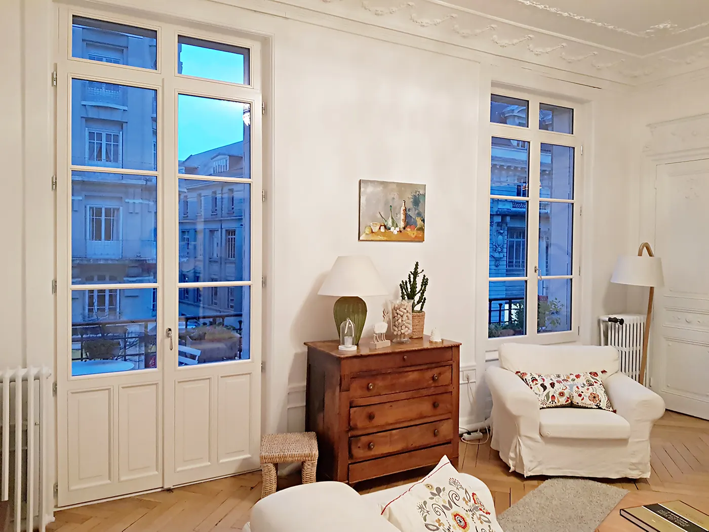 Pièce haussmannienne blanche et rangée, portes-fenêtres et commode ancienne